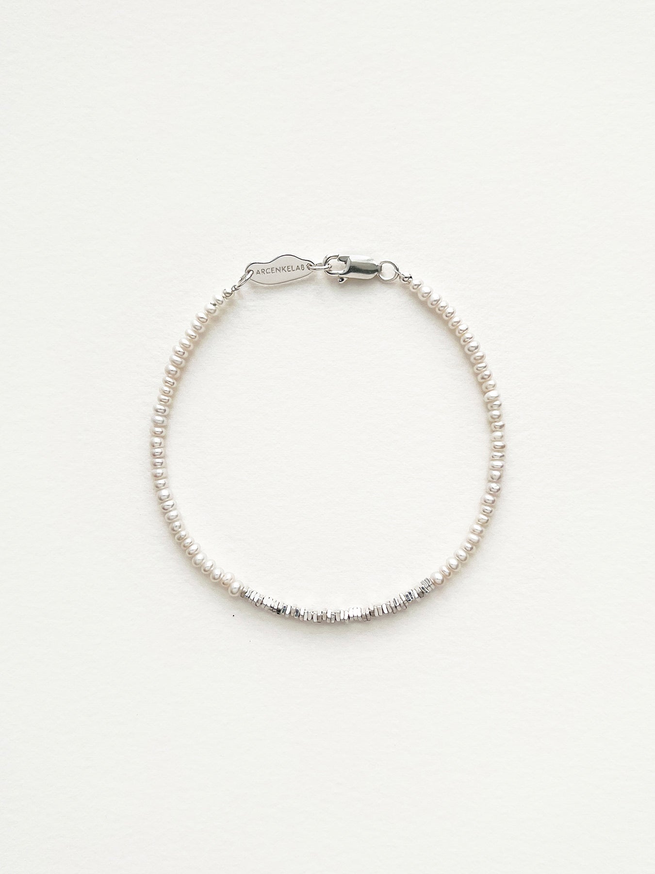 Discover the Arcenkelab Mini Pearl and Silver Necklace—a timeless blend of elegance and simplicity. Perfect for any occasion, this handcrafted piece features delicate pearls and sleek silver, making it versatile for all styles, genders, and ages.