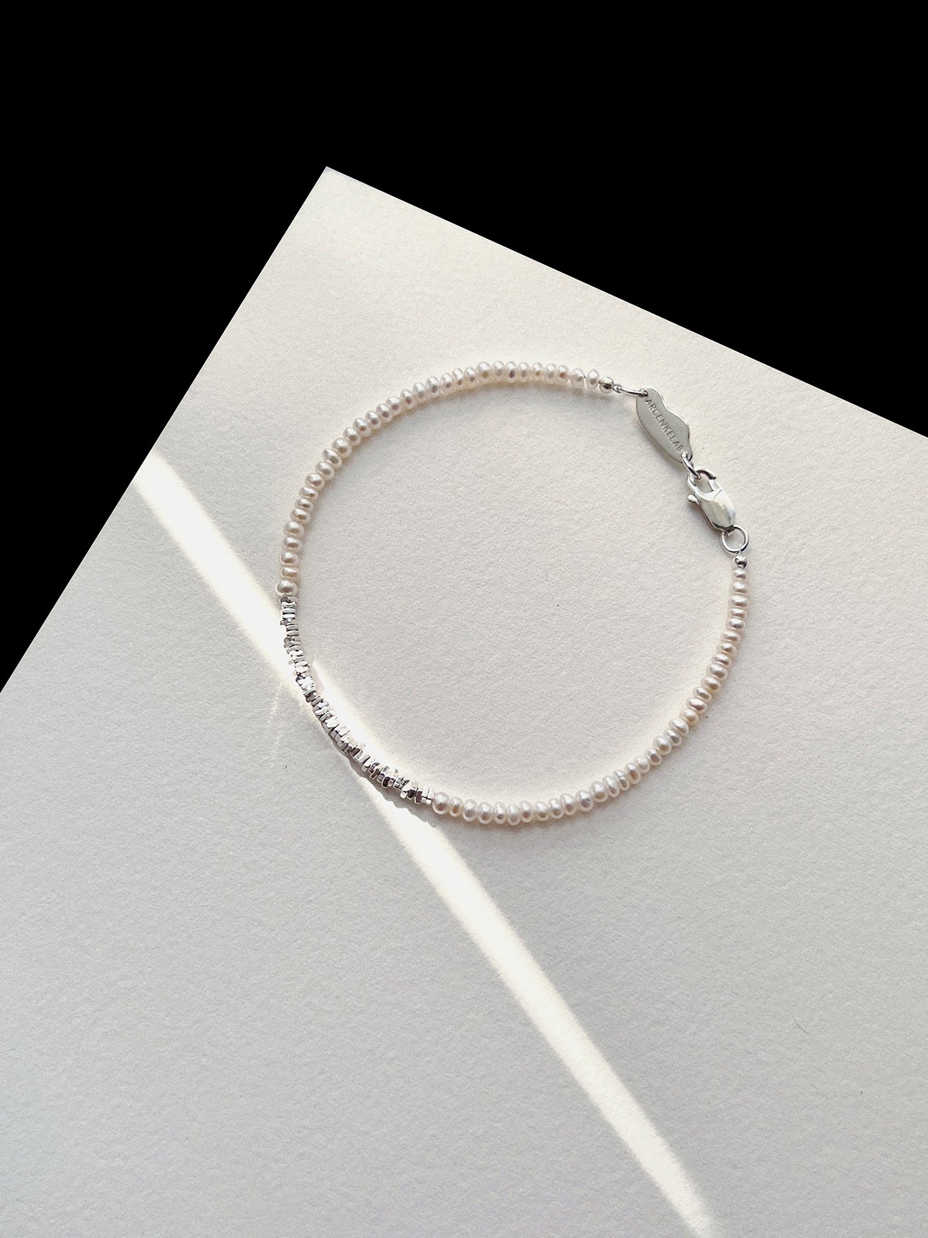 Discover the Arcenkelab Mini Pearl and Silver Necklace—a timeless blend of elegance and simplicity. Perfect for any occasion, this handcrafted piece features delicate pearls and sleek silver, making it versatile for all styles, genders, and ages.
