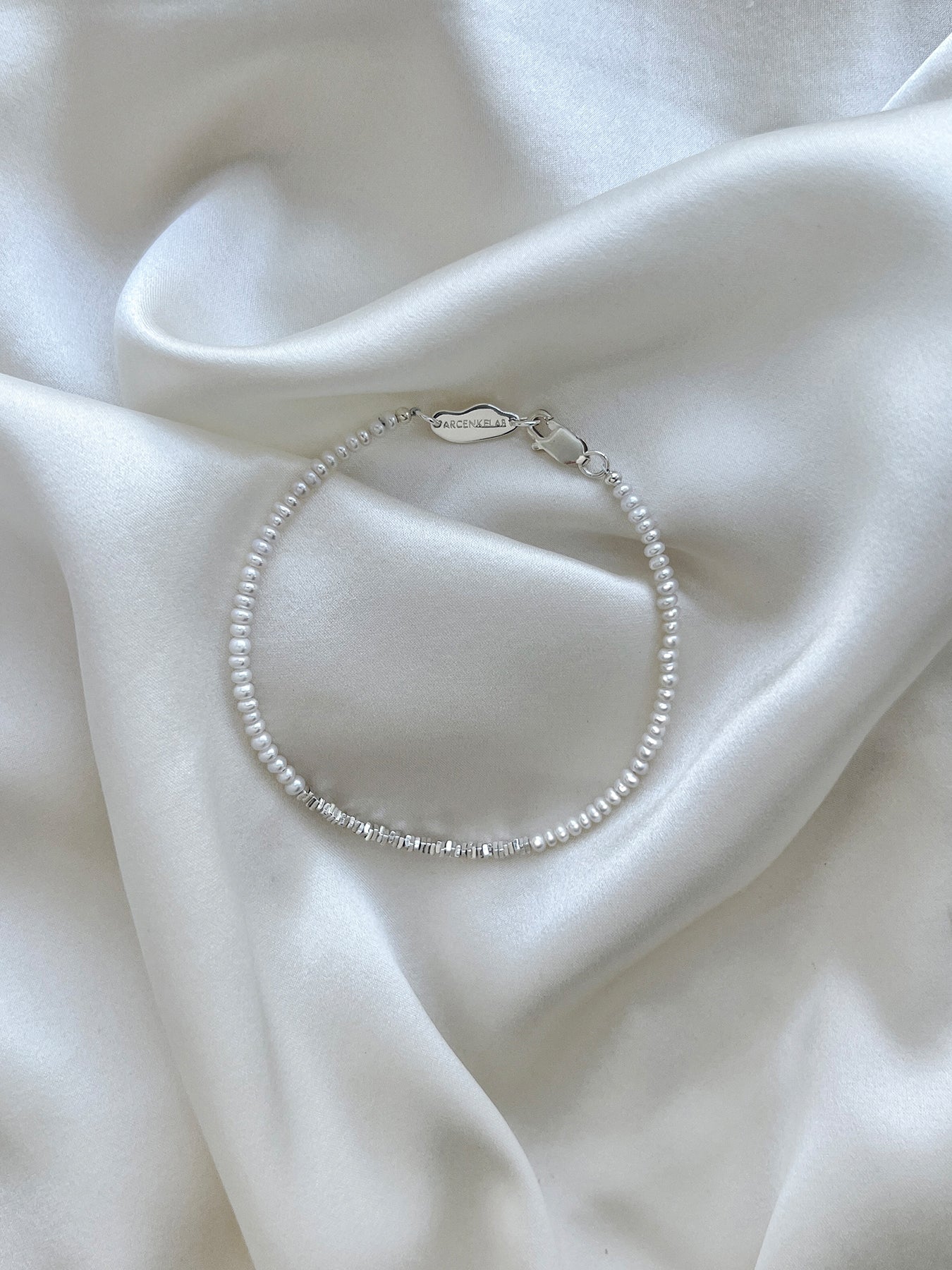 Discover the Arcenkelab Mini Pearl and Silver Necklace—a timeless blend of elegance and simplicity. Perfect for any occasion, this handcrafted piece features delicate pearls and sleek silver, making it versatile for all styles, genders, and ages.